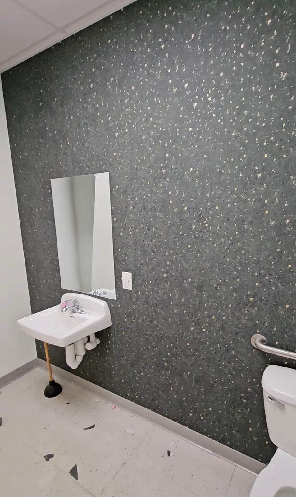 Commercial bathroom with dark terrazzo-print wallpaper installed in Louisville, KY