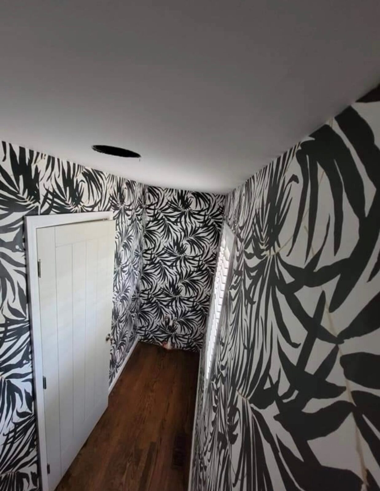 Hallway with bold black and white tropical leaf wallpaper installed in Louisville, KY